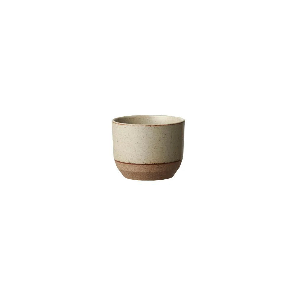 A small ceramic cup with a speckled beige upper body and a contrasting brown base, centered on a plain white background.