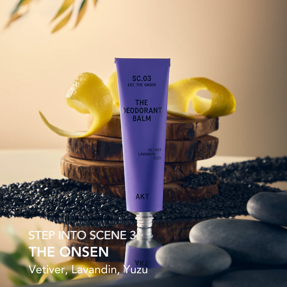 Purple deodorant balm tube with 'The Onsen' description on a natural background with stones and leaves.