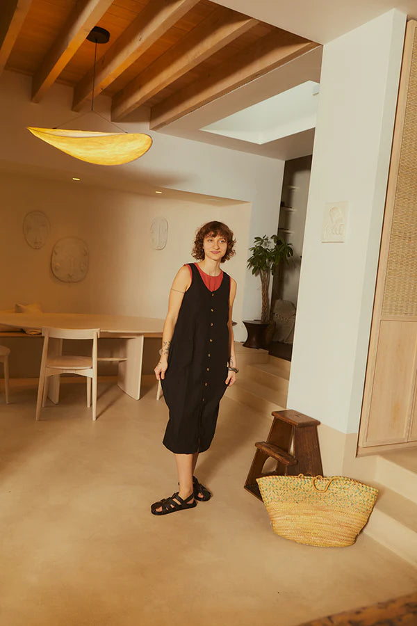 lack sleeveless LF Markey dress with button details with a red sleeveless top underneath photographed on a woman  in a natural coloured home 