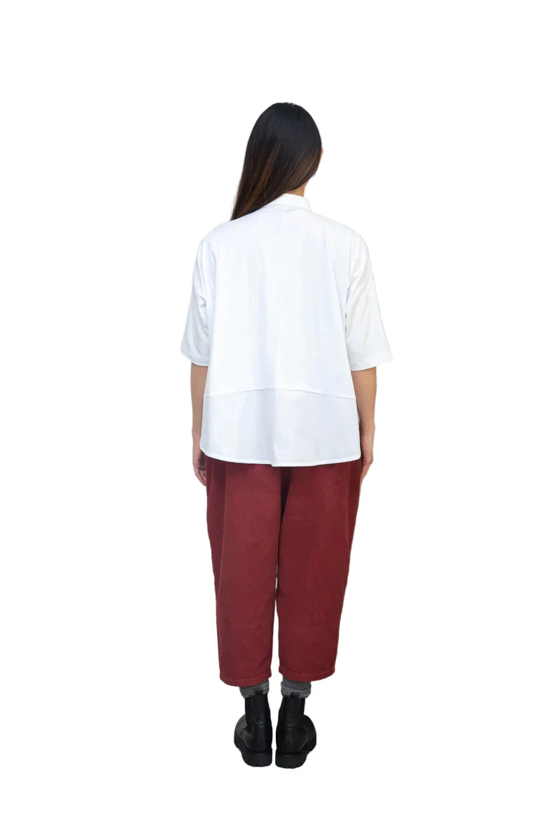 Person wearing Beaumont Organic white cotton and Jersey shirt with a Peter Pan collar alongside rust coloured cord trousers 