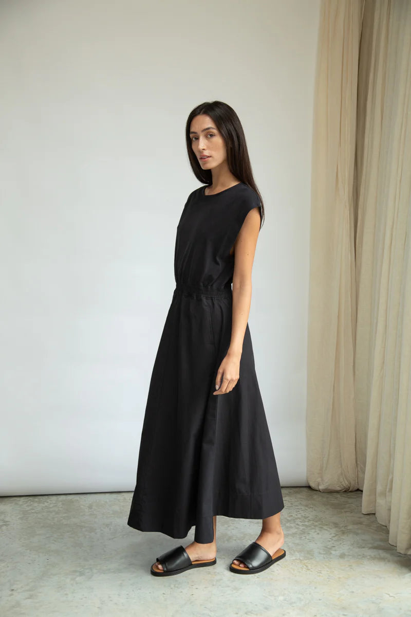 Woman wearing a black dress standing against a plain background