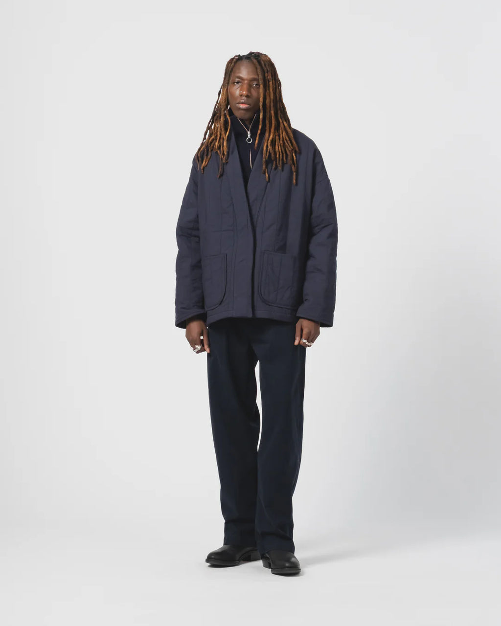 Person wearing a navy Eat Dust Kimono inspired padded jacket against a white background 