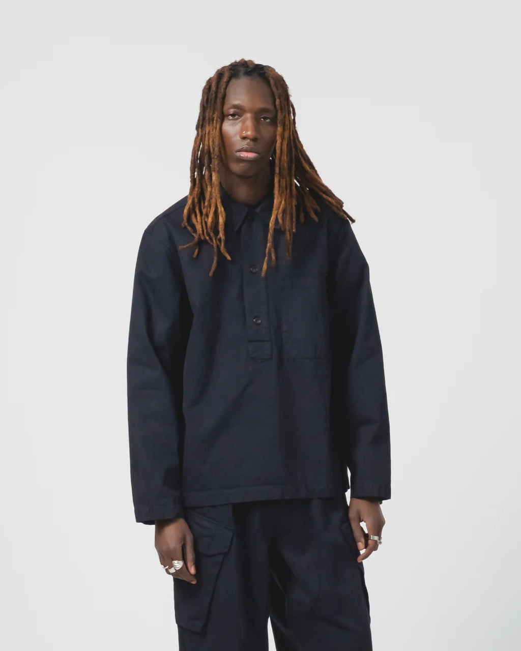 Person wearing a dark blue Eat Dust shirt and trousers  on a light grey background