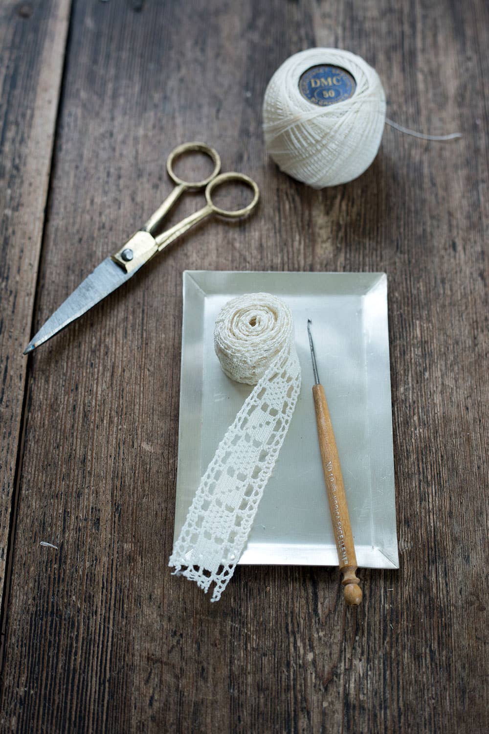 Scissors, lace, and yarn on a wooden surface