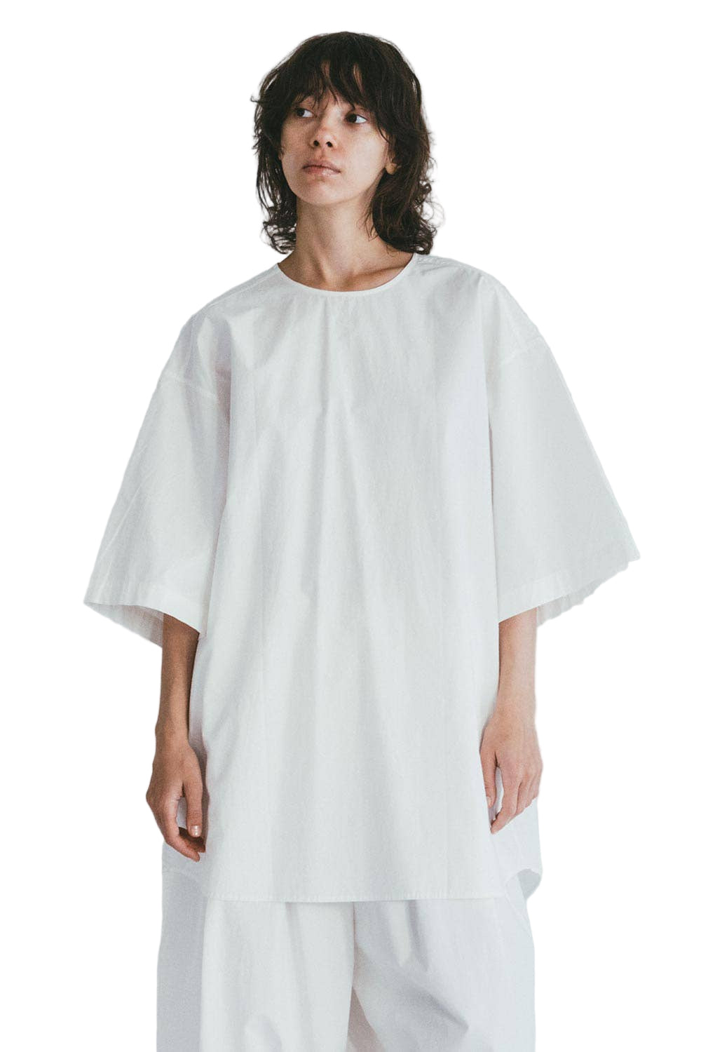 Person wearing a white Mii Thaaii oversized white shirt on a plain background
