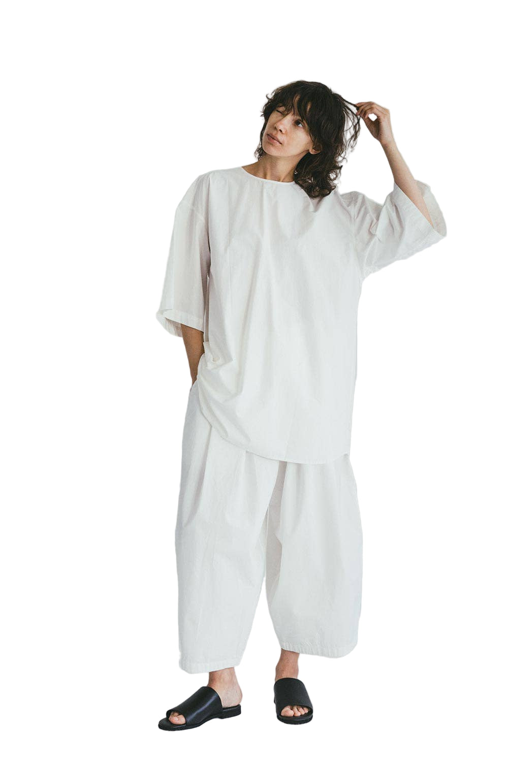 Person wearing a white Subash oversized top by Mii Thaaii with a plain background