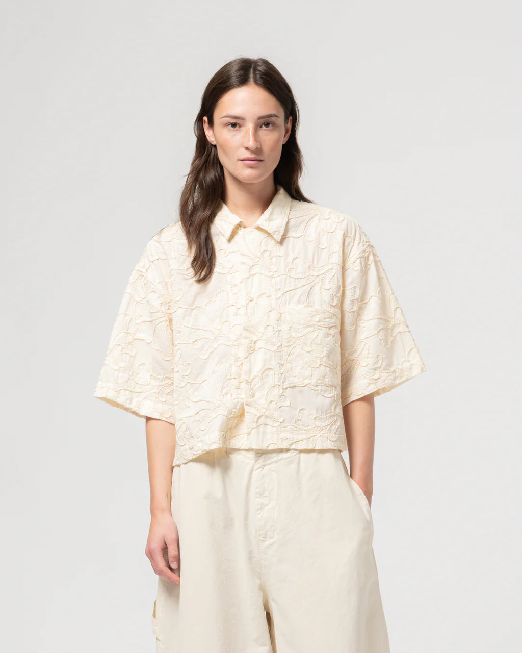 Woman wearing a light-colored blouse and pants on a white background