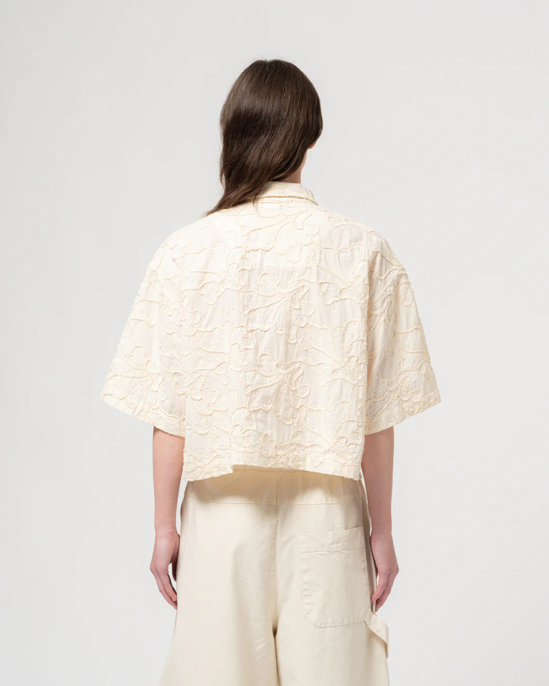 Woman wearing a cream textured Girls of Dust boxy shirt and pants on a white background
