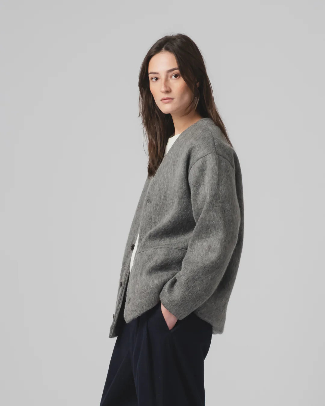 Woman wearing a Girls of Dust  grey cardigan on a plain background