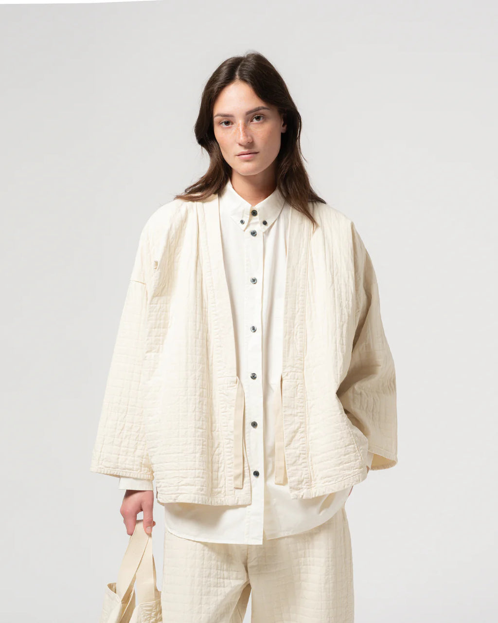 Person wearing a cream-colored outfit against a white background