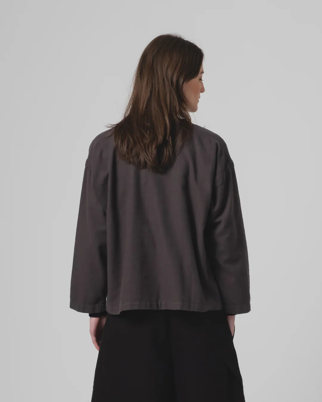 Person wearing a Girls of Dust dark grey top on a plain background