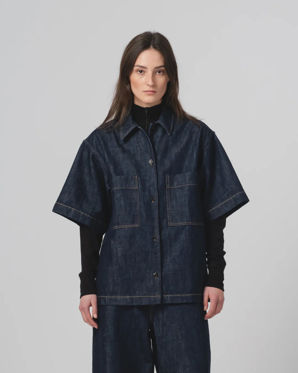 Person wearing a Girls of Dust dark denim shirt  and trousers on a plain background