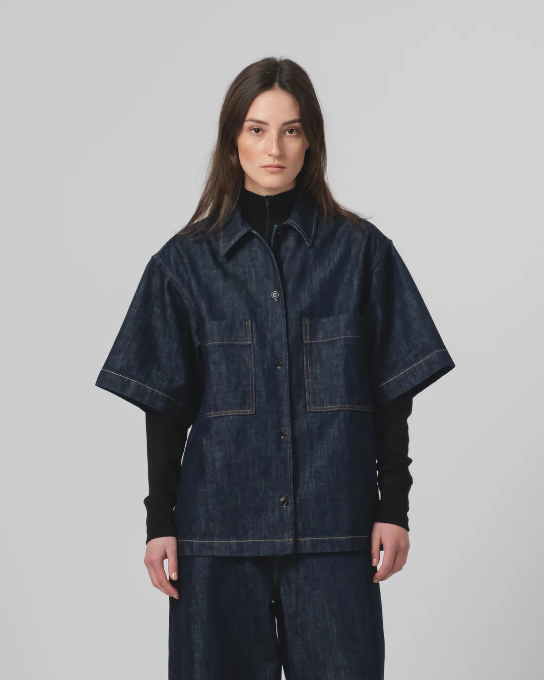 Person wearing a Girls of Dust dark denim shirt  and trousers on a plain background