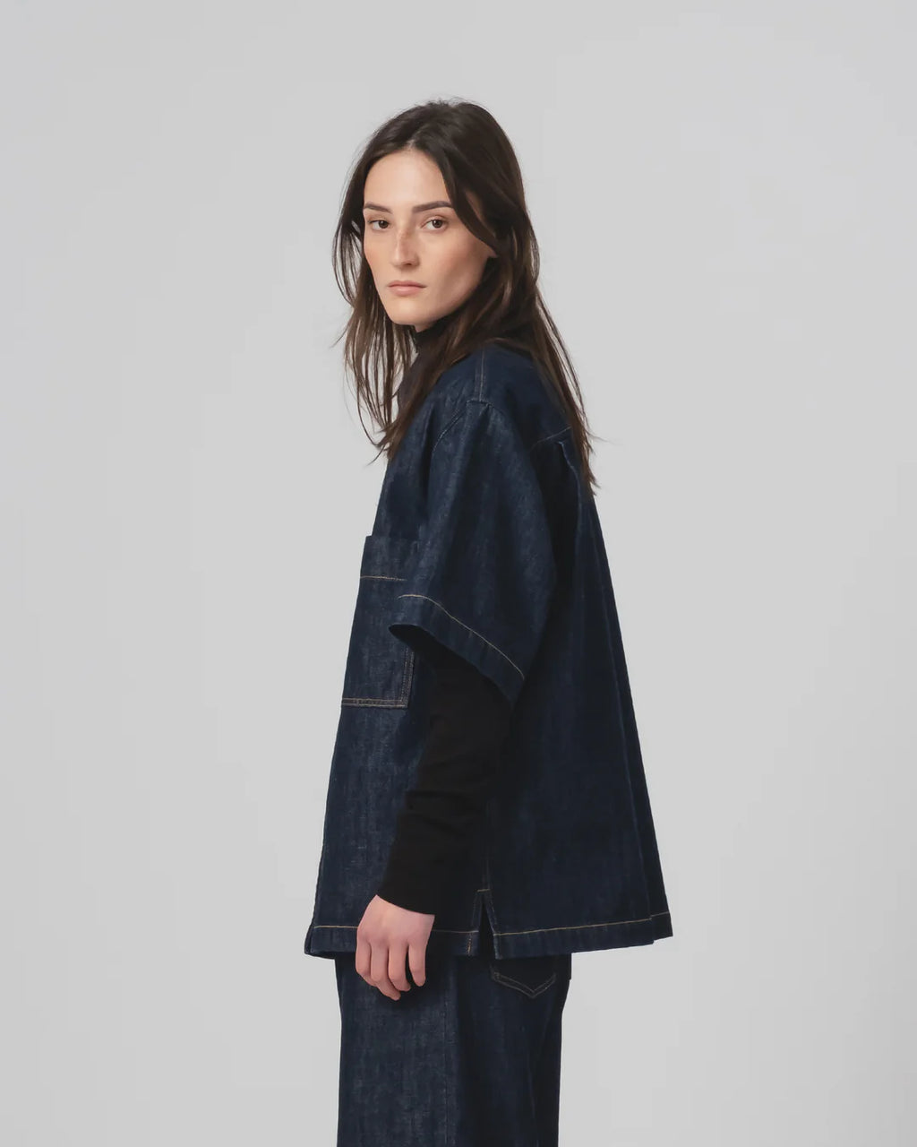 Woman wearing a Girls of Dust dark denim shirt  on a plain background