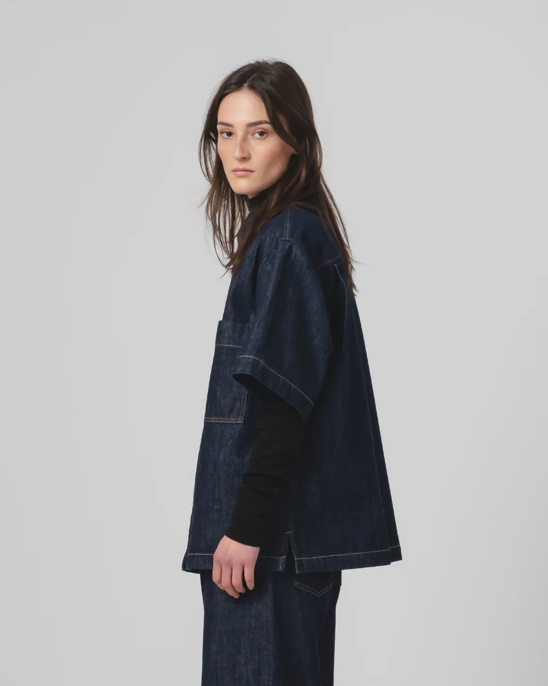 Woman wearing a Girls of Dust dark denim shirt  on a plain background
