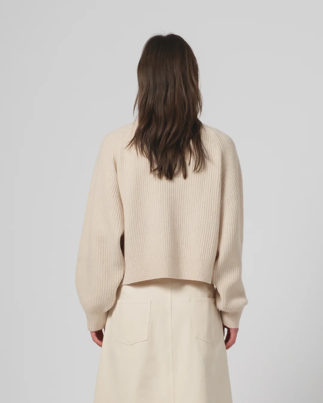 Person wearing a Girls of Dust beige ribbed sweater and pants on a plain background