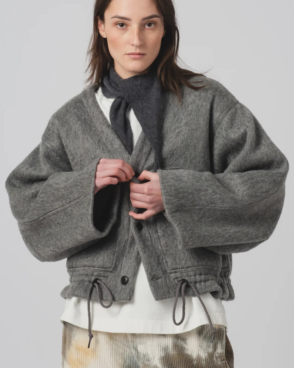 Person wearing a Girls of Dust grey oversized jacket with a plain background