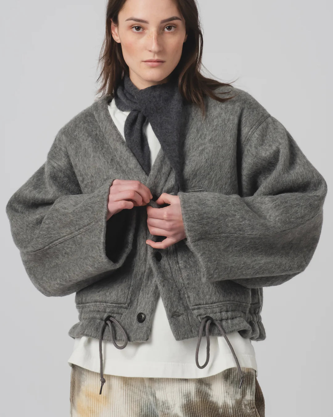 Person wearing a Girls of Dust grey oversized jacket with a plain background