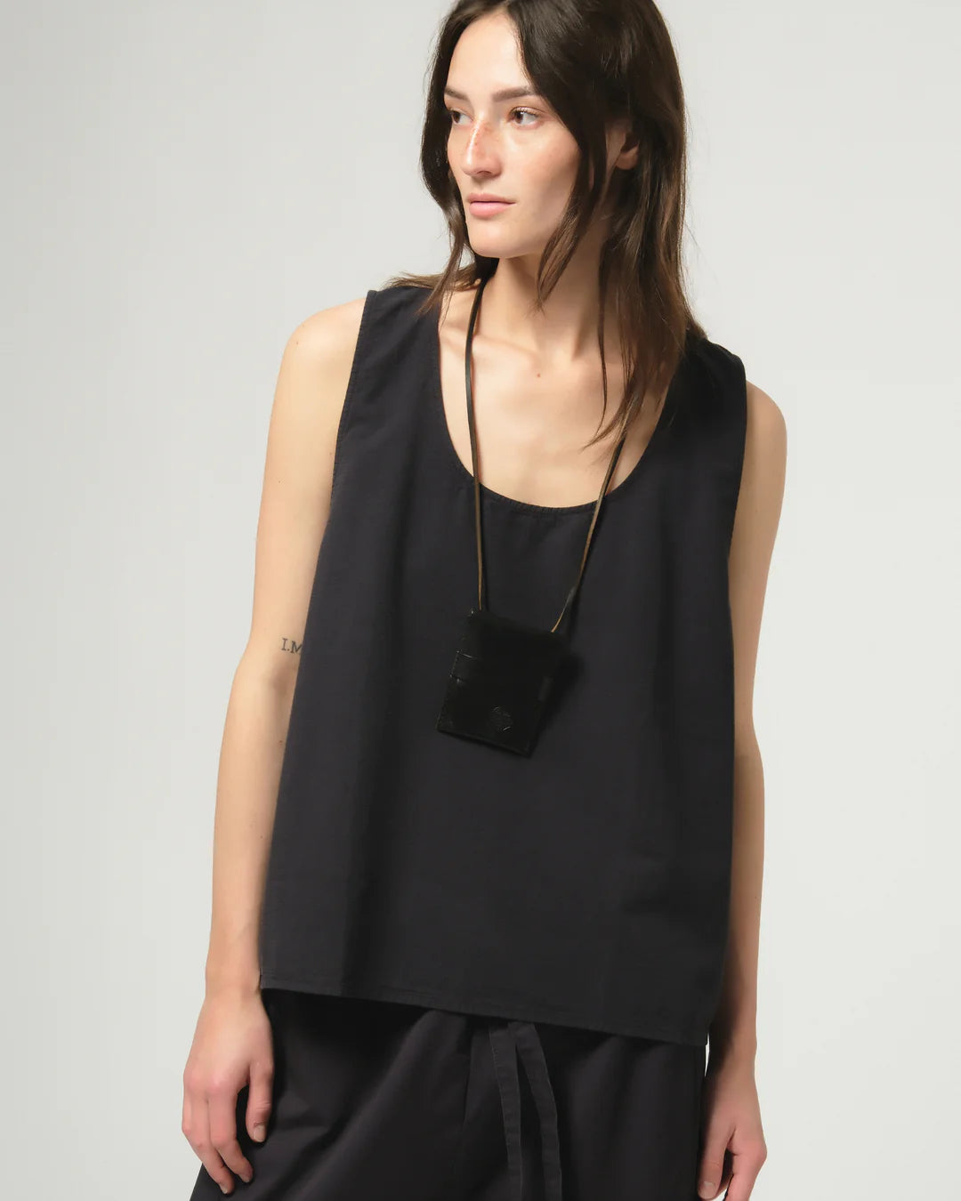 Woman wearing a dark navy Girls of Dust sleeveless top on a white background