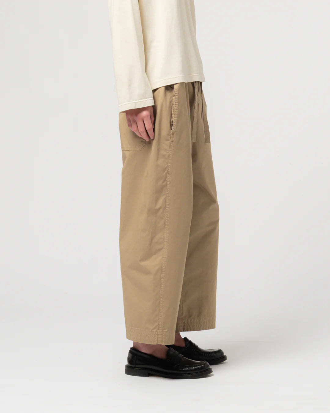 Person wearing beige pants and a cream top on a white background