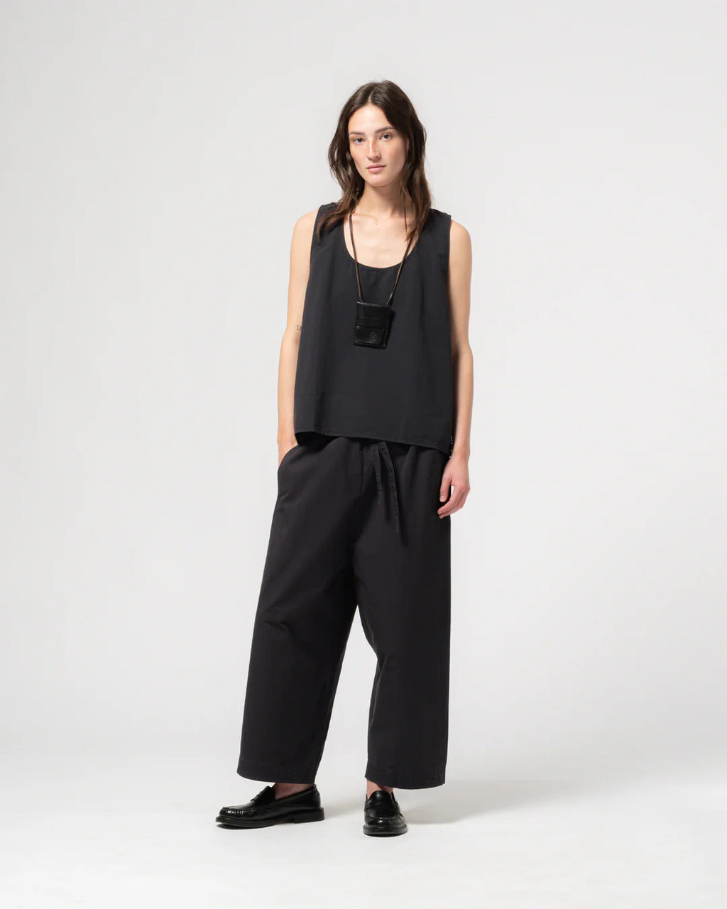 Woman wearing a dark navy sleeveless top and wide-leg pants on a white background