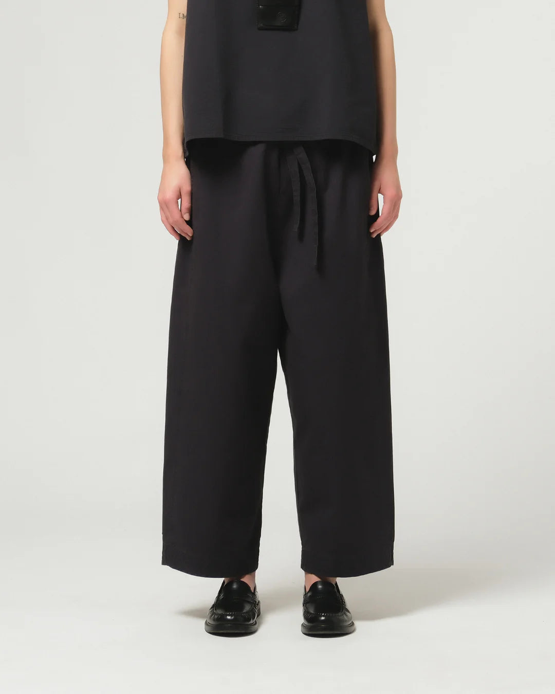 Person wearing dark navy Girls of Dust wide-leg trousers on a white background