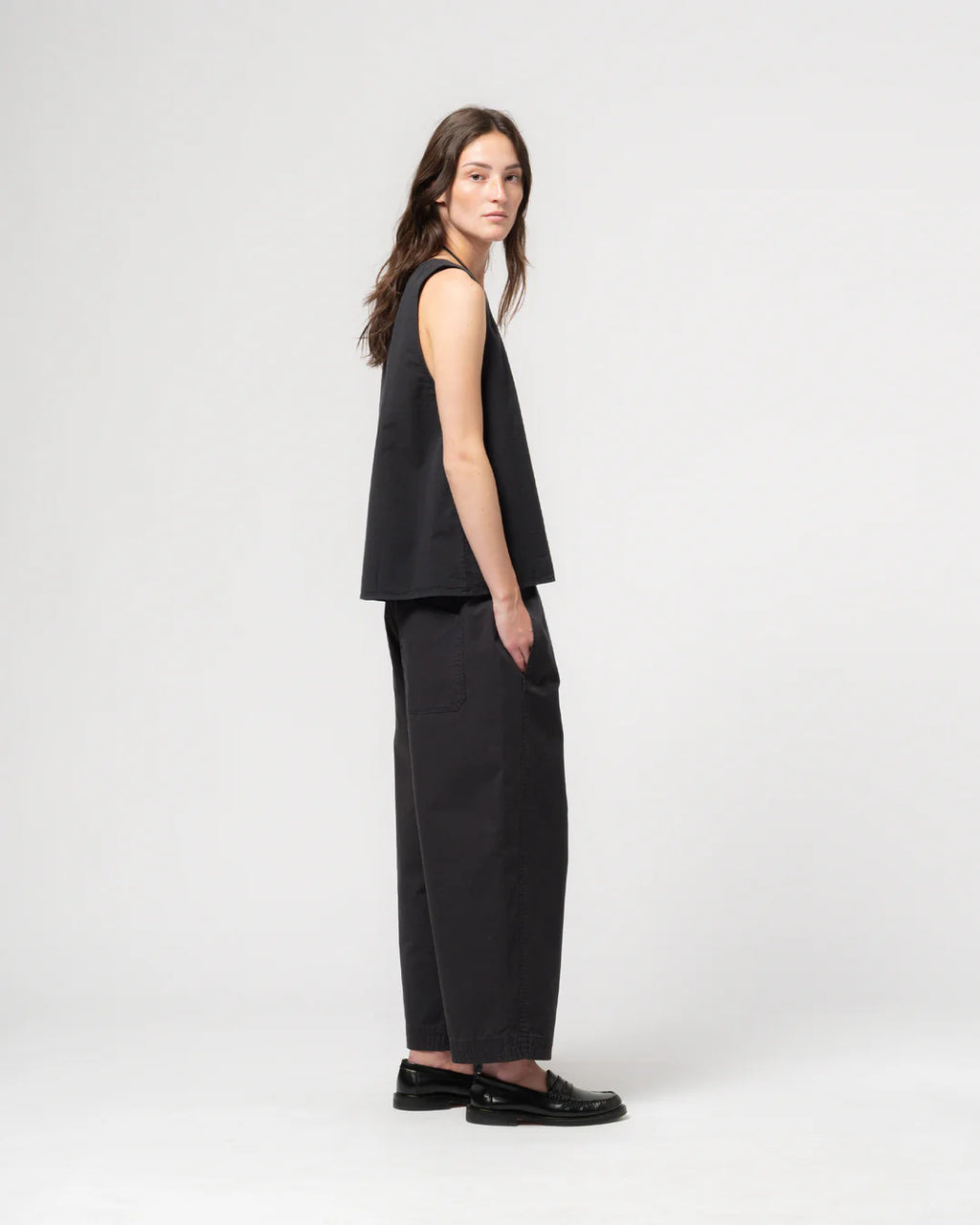 Woman wearing a black sleeveless top and pants on a white background