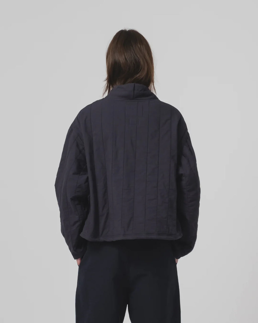 Person wearing a dark navy Girls of Dust jacket and trousers on a plain background