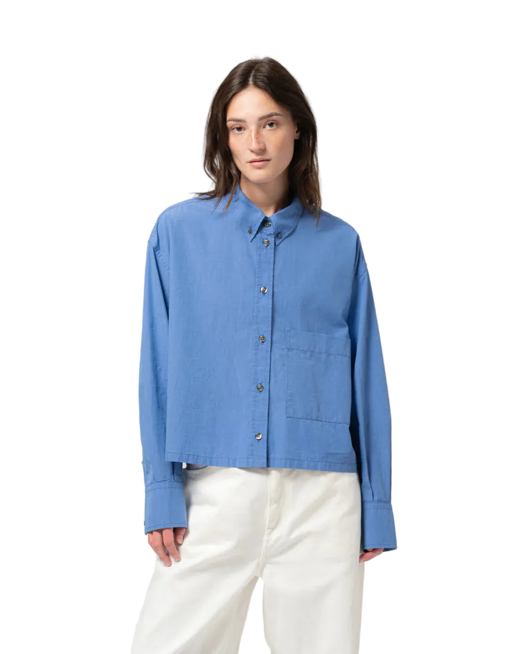Person wearing a blue cotton shirt and white pants on a light gray background