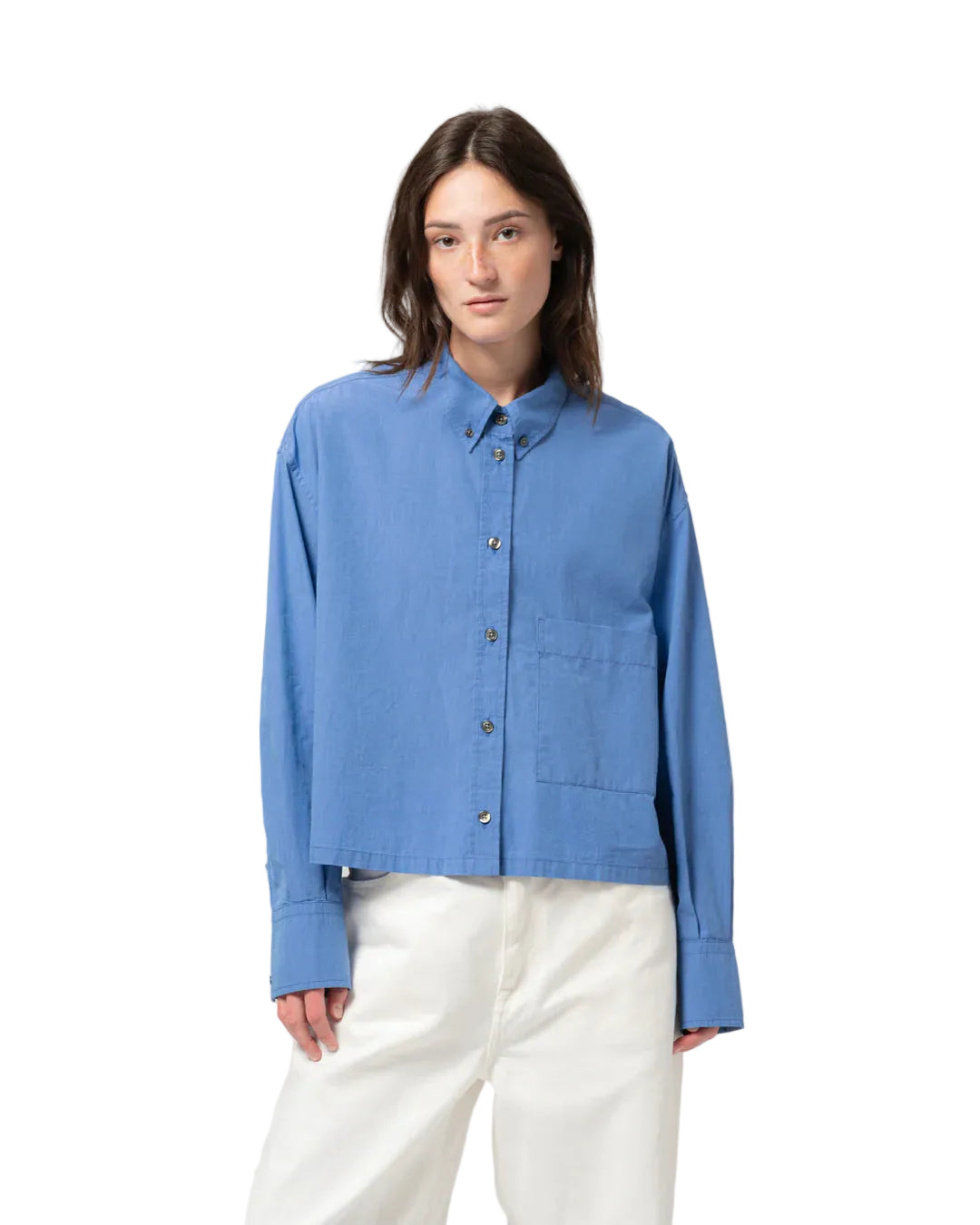 Person wearing a blue cotton shirt and white pants on a light gray background