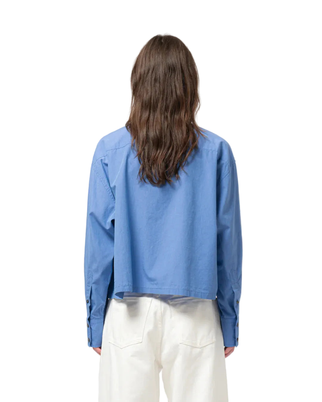 Person wearing a blue shirt and white trousers on a plain background