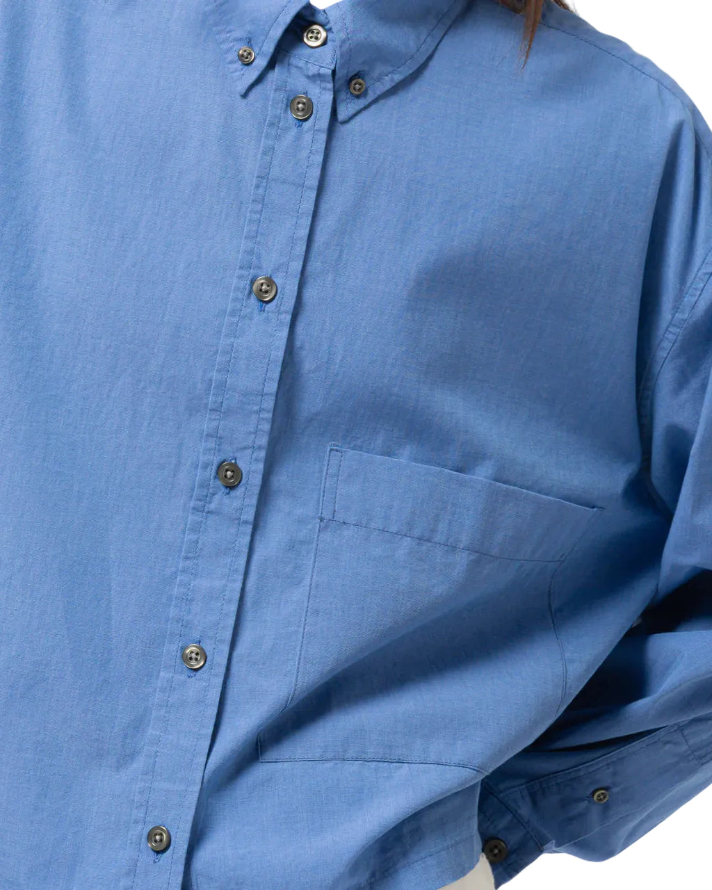 Close-up of a blue Girls of Dust button-up shirt on a white background