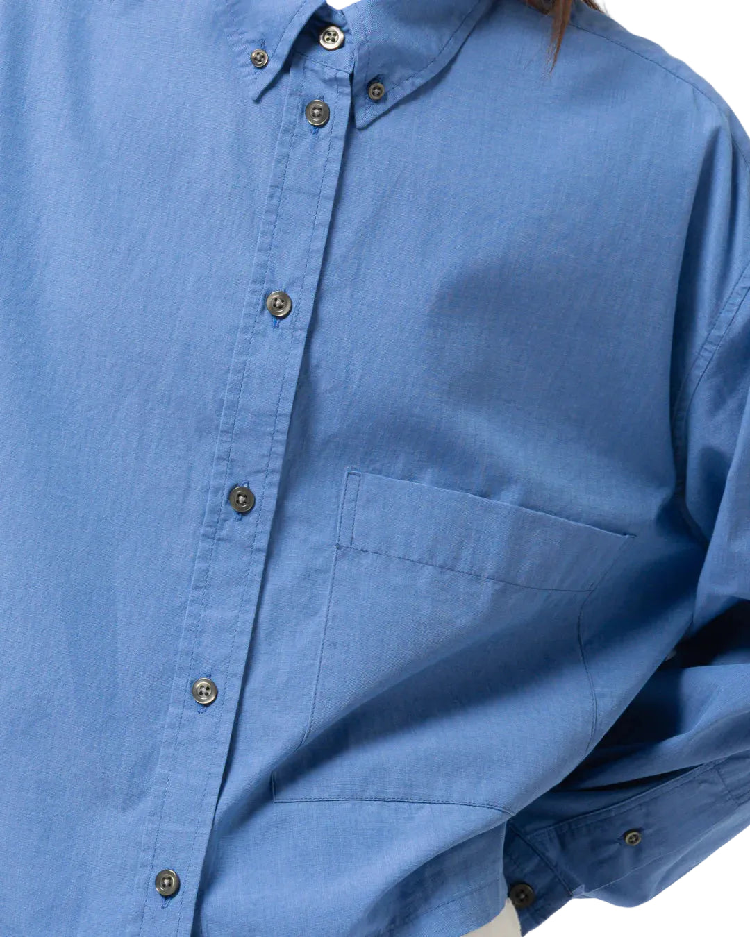 Close-up of a blue Girls of Dust button-up shirt on a white background