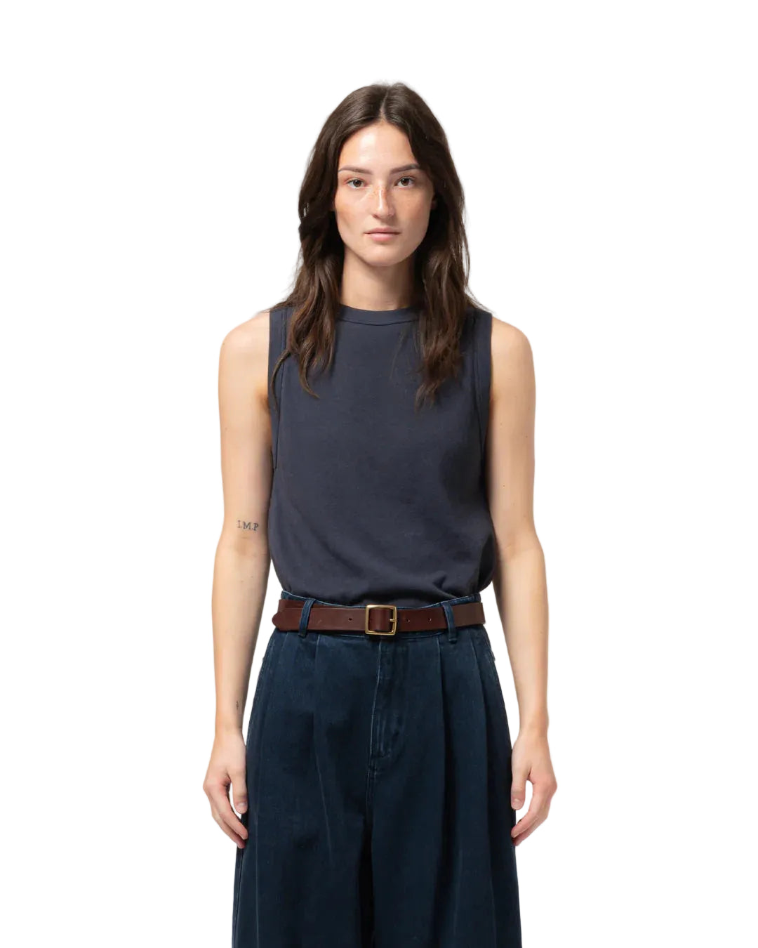 Woman wearing a sleeveless navy top and dark pants on a light gray background