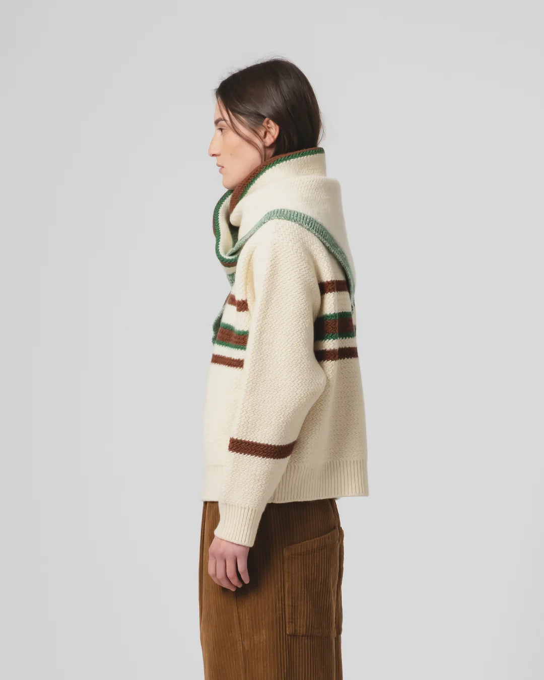 Person wearing a cream sweater with Girls of Dust triangular woollen scarf with green, brown, and beige pattern on a white background