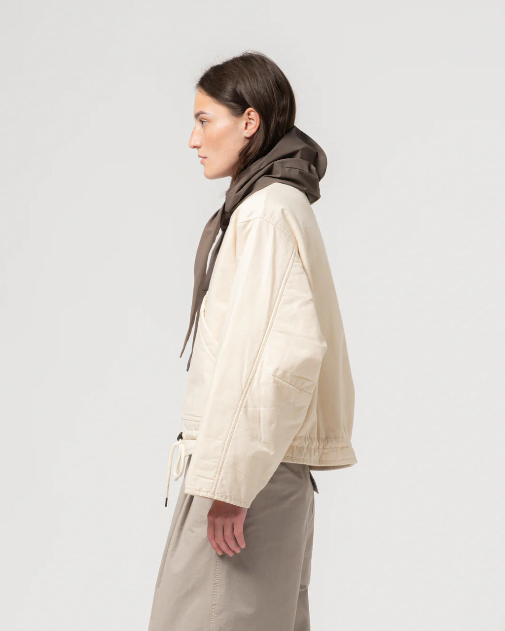 Woman wearing a beige jacket and scarf on a white background