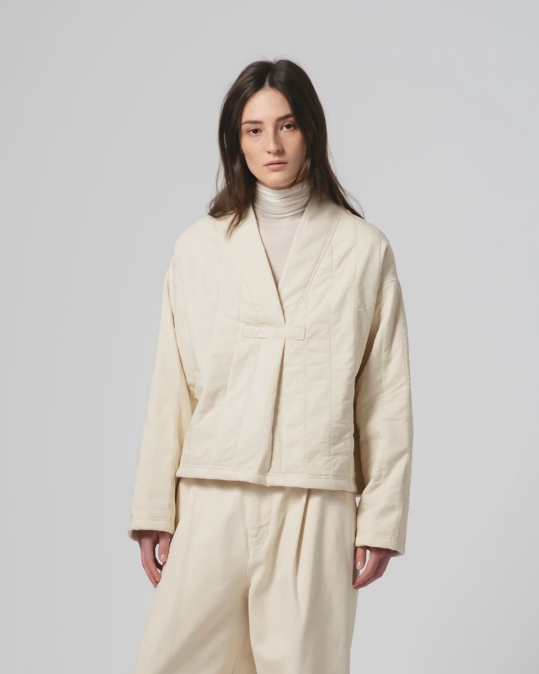 Person wearing a ecru Girls of Dust quilted jacket and pants on a plain background