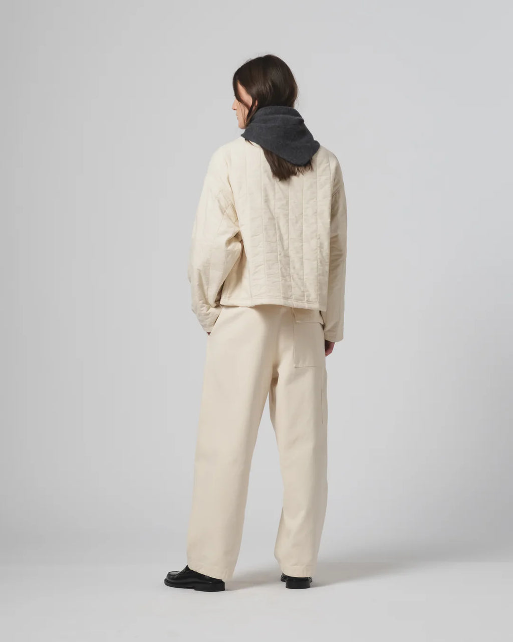 Person wearing an ecru Girls of Dust  quilted jacket and pants on a plain background