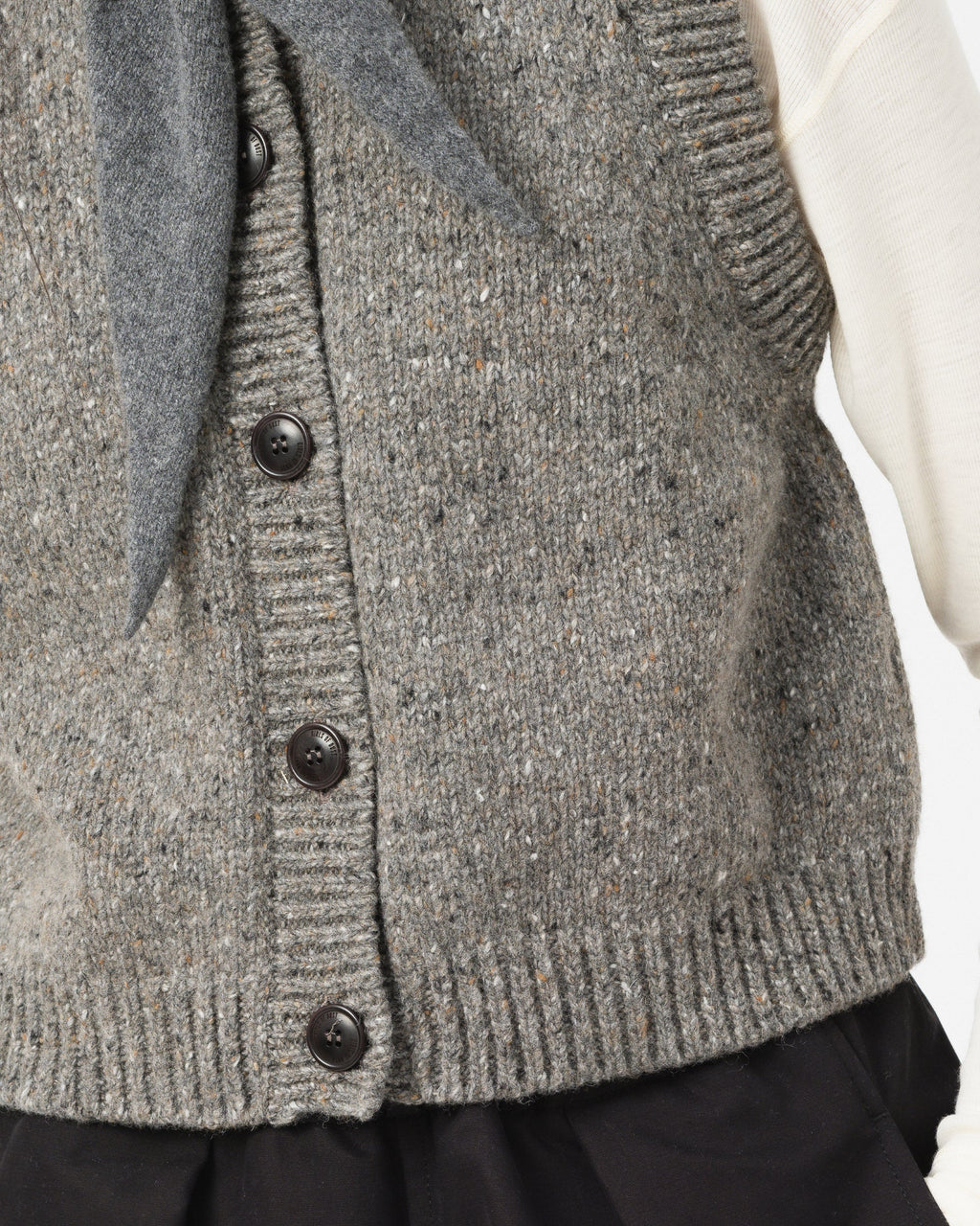 Close-up of Girls of Dust grey knit cardigan vest with dark buttons, worn over a white top 