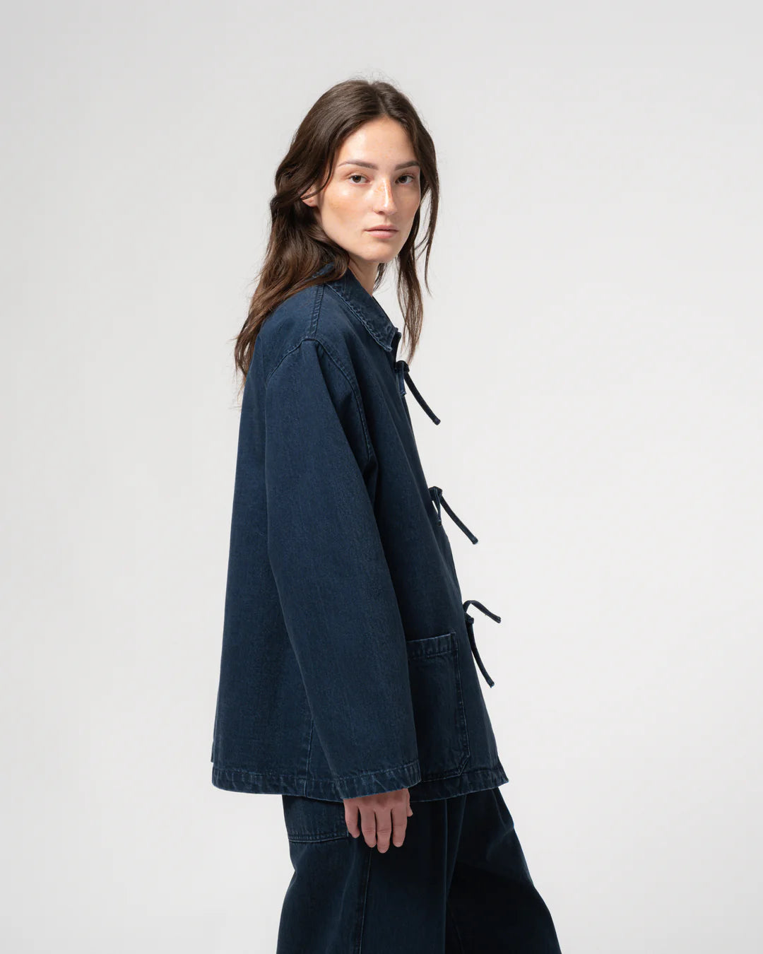 Woman wearing a dark blue jacket with black drawstrings on a white background