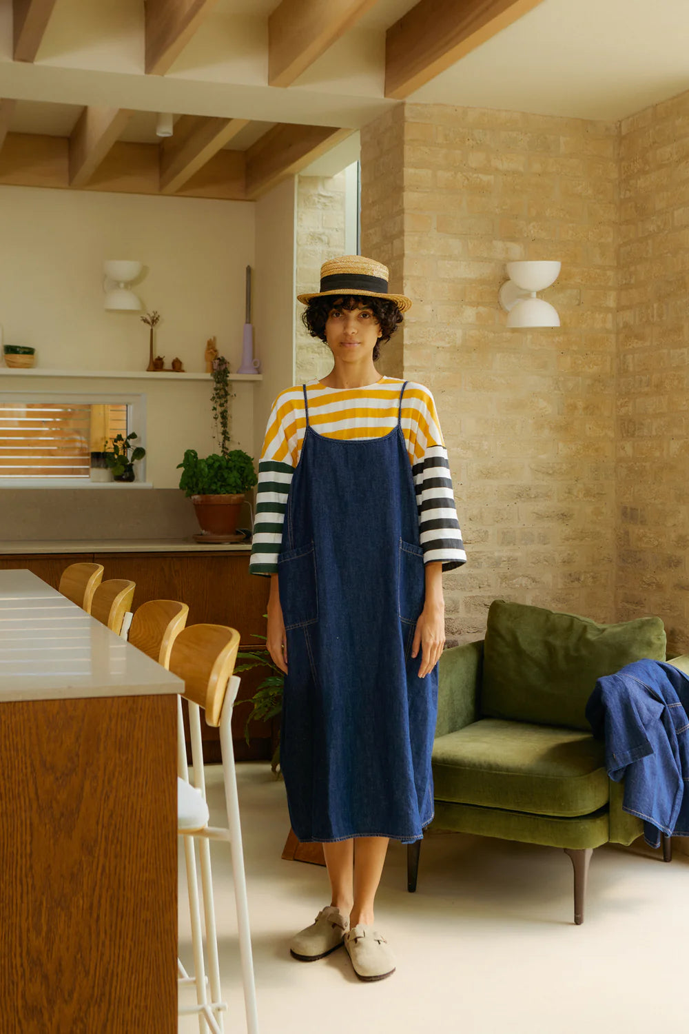 Woman in a LF Markey blue denim dress and yellow striped shirt standing in a modern kitchen.