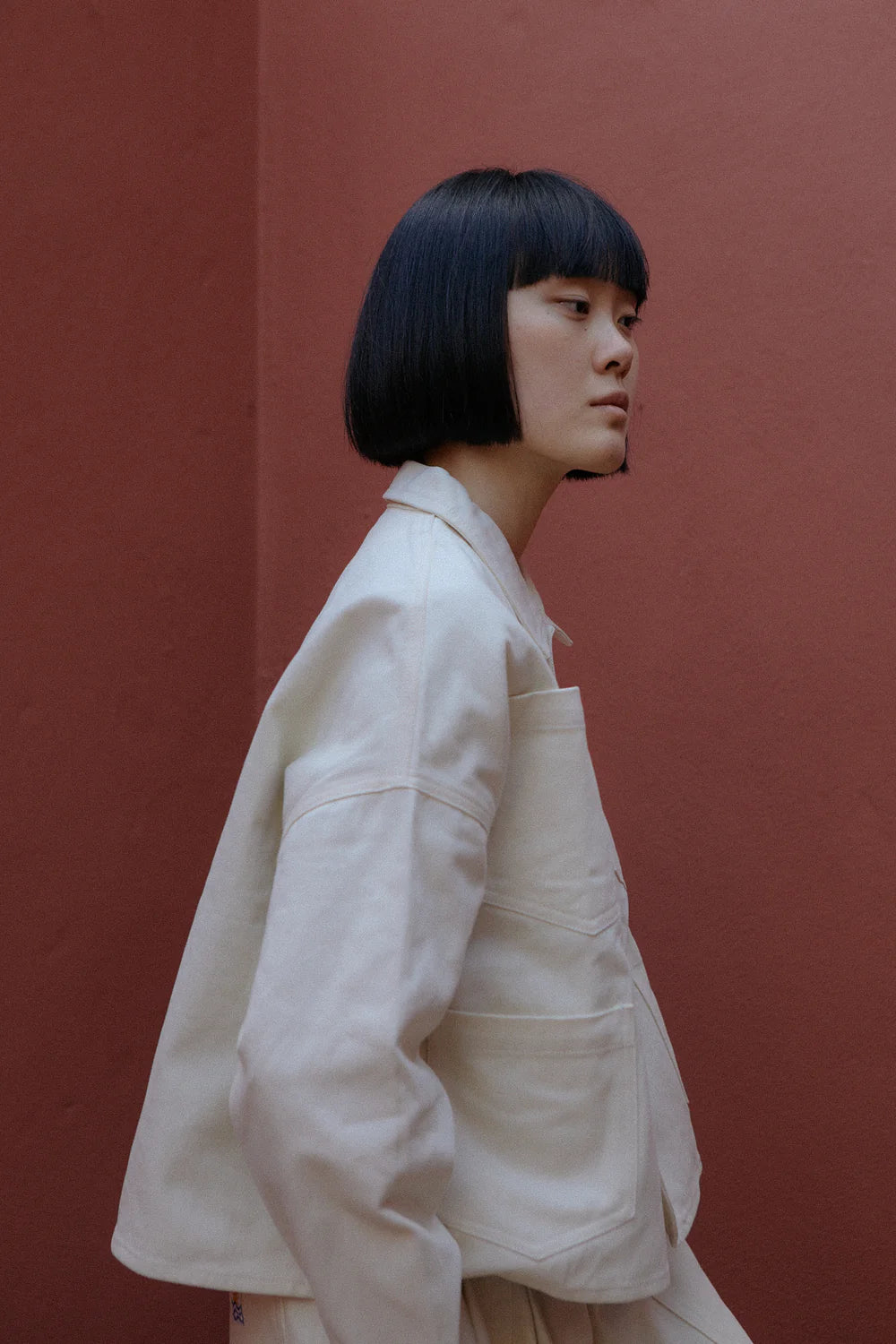 Person wearing a beige jacket against a red background