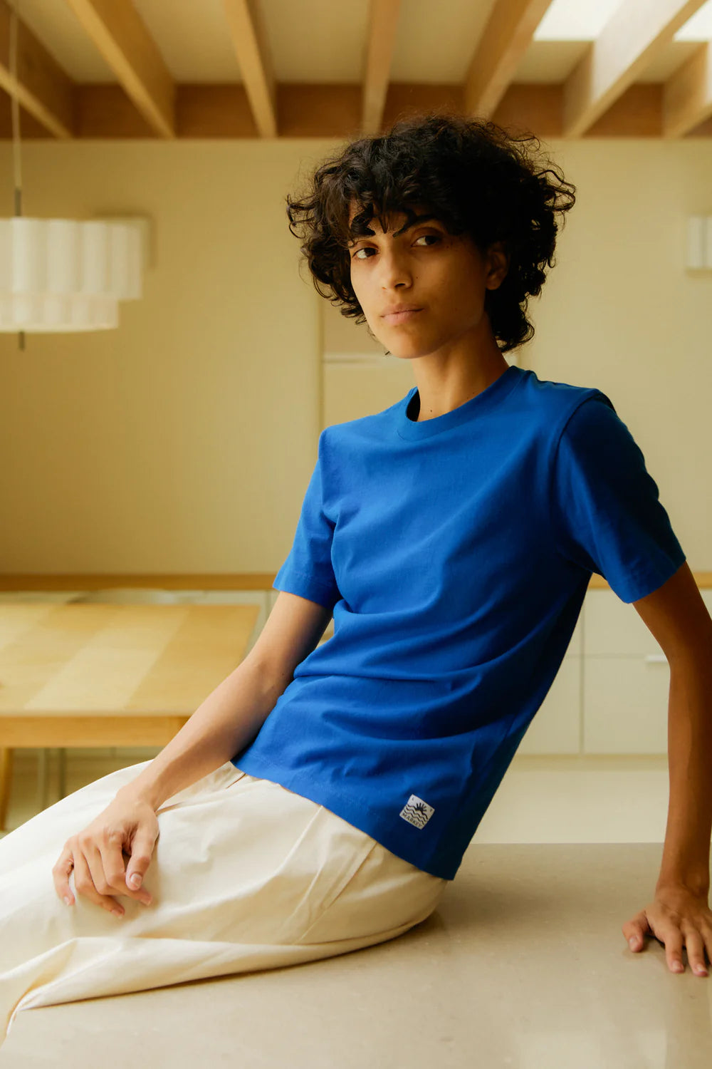 Person wearing a blue colbolt t-shirt sitting on a wooden floor.