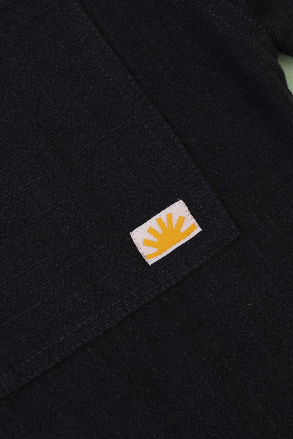 Close-up of a navy fabric with a logo featuring a yellow sun on a white background.