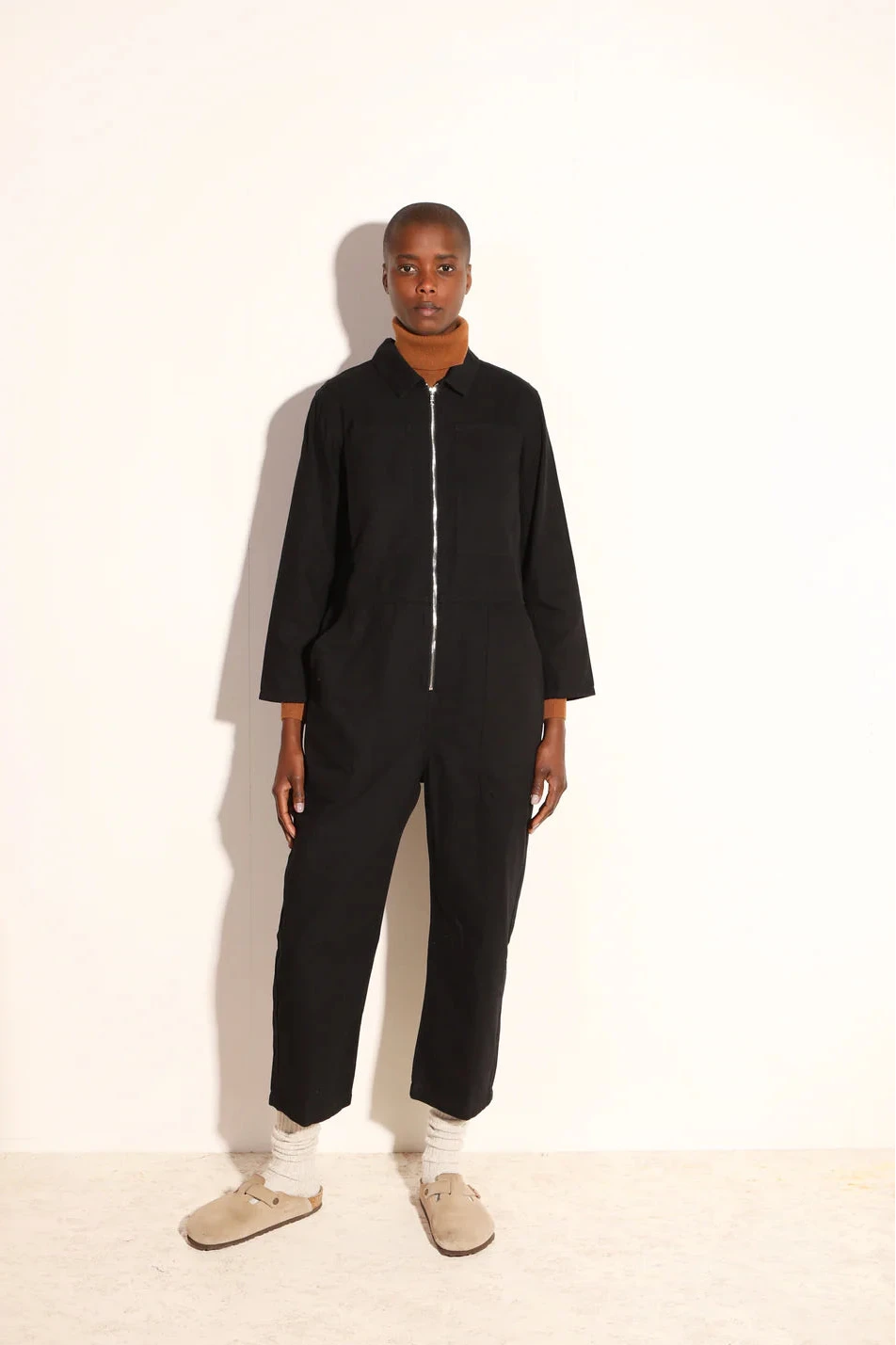 Person wearing a black LF Markey Jumpsuit with a zip on a white background
