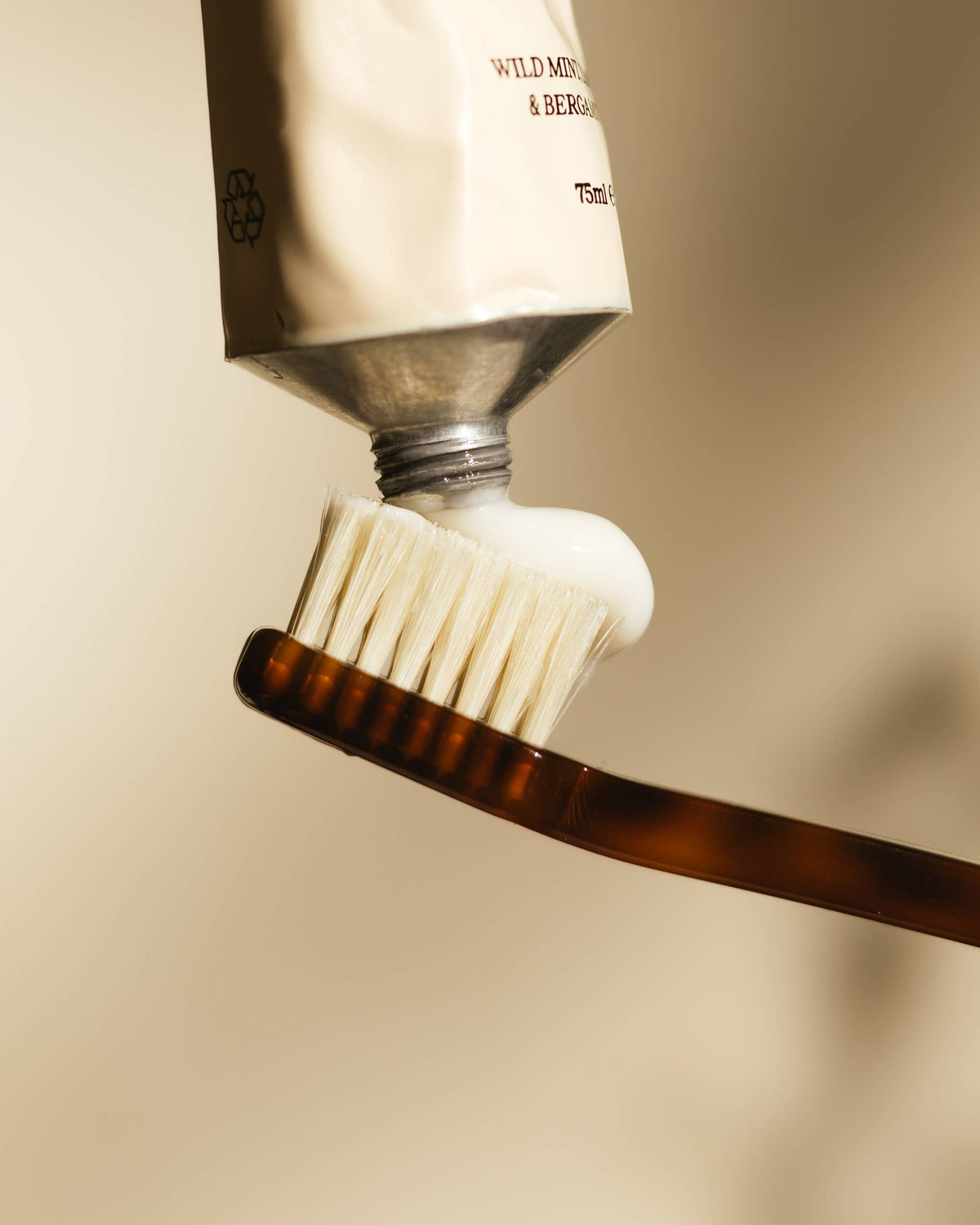 Close-up of a toothbrush with Laro toothpaste being applied on a beige background