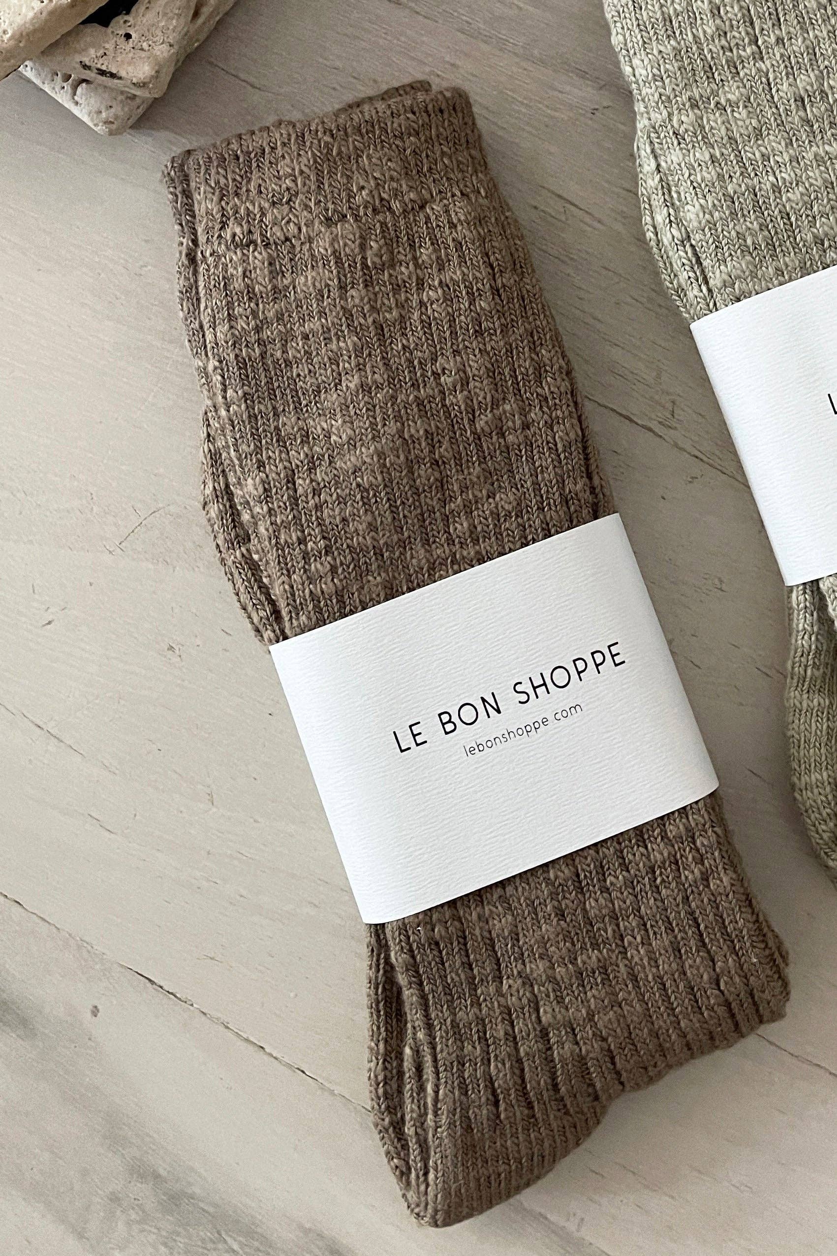 Brown socks with a 'Le Bon Shoppe' label on a light wooden surface