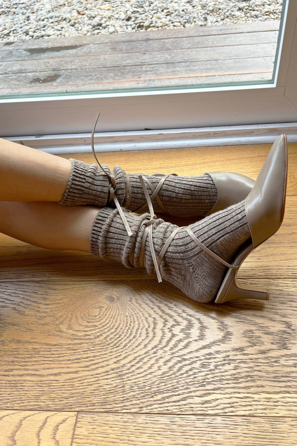 White high-heeled shoes with brown ribbed Le Bon Shoppe socks on a wooden floor.