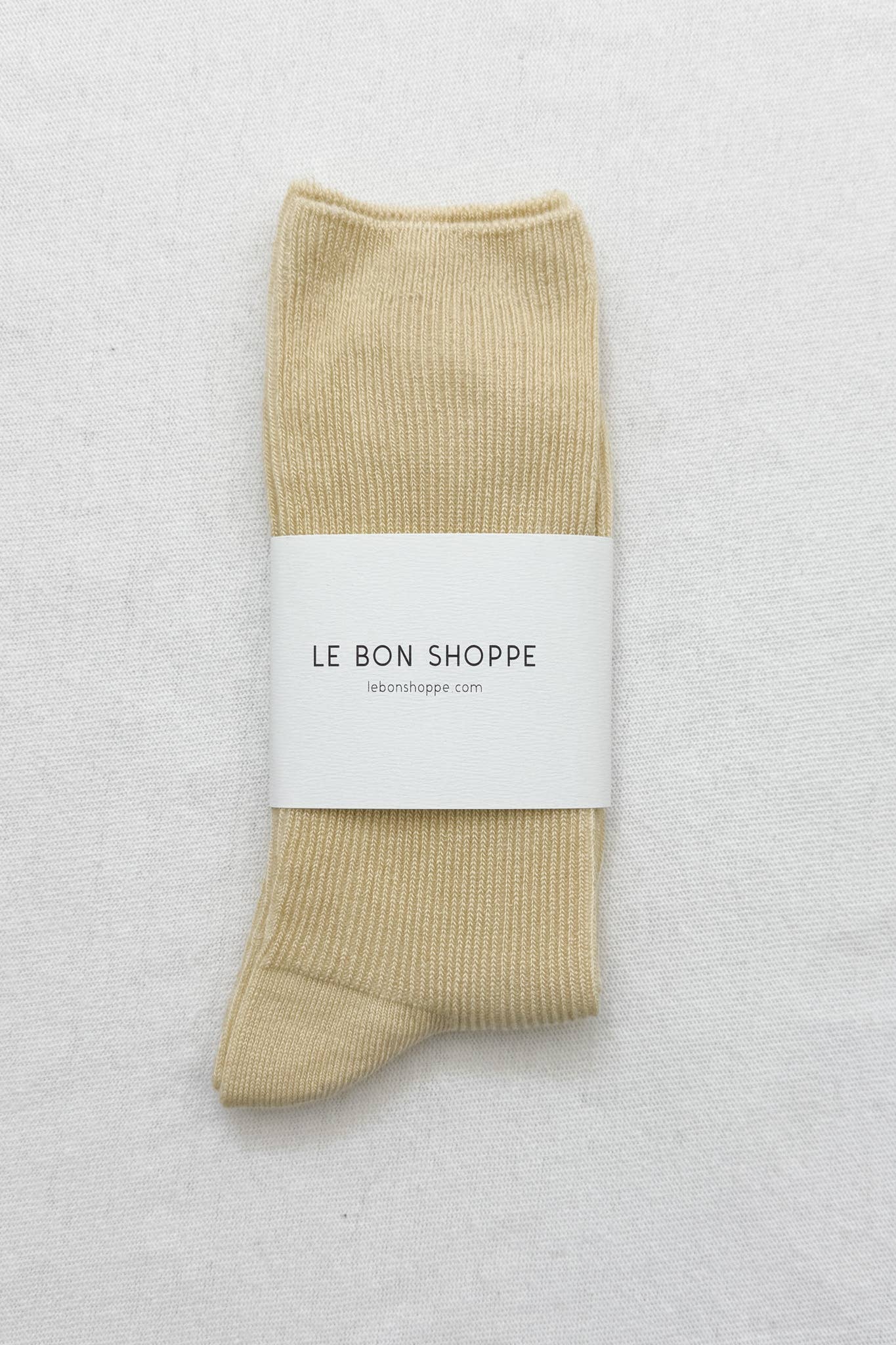 Le Bon Shoppe yellow sock with a white label on a light gray background
