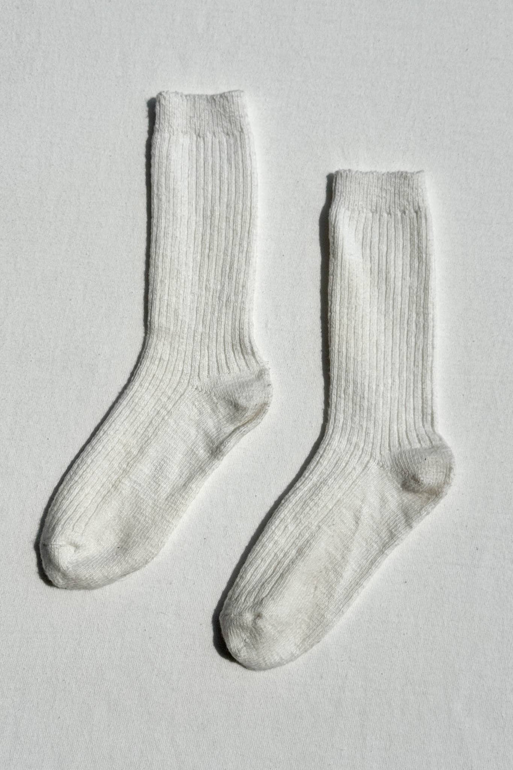 Pair of white Le Bon Shoppe socks on a light grey background